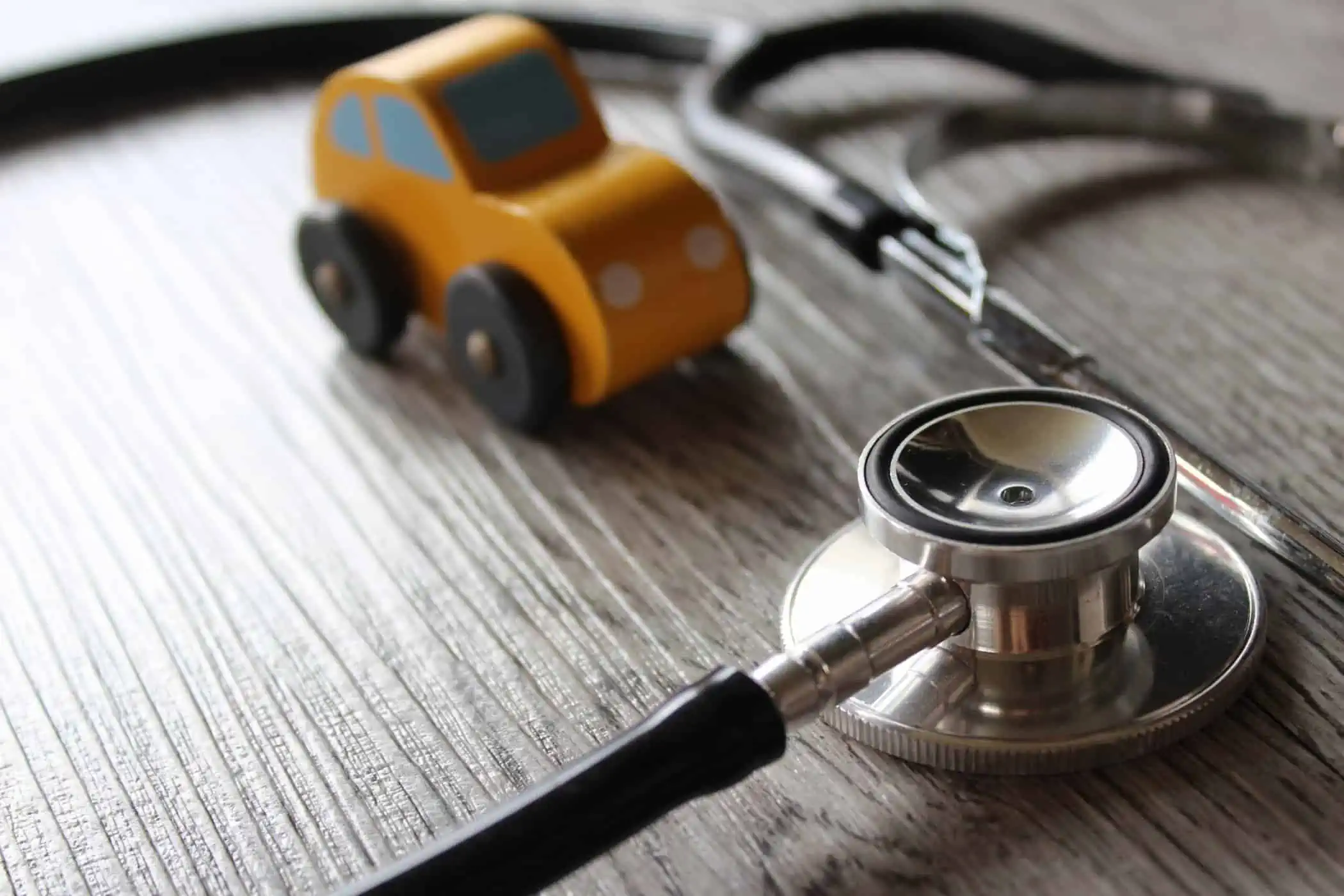 Ein Stethoskop und ein Spielzeugauto auf einem Holztisch.